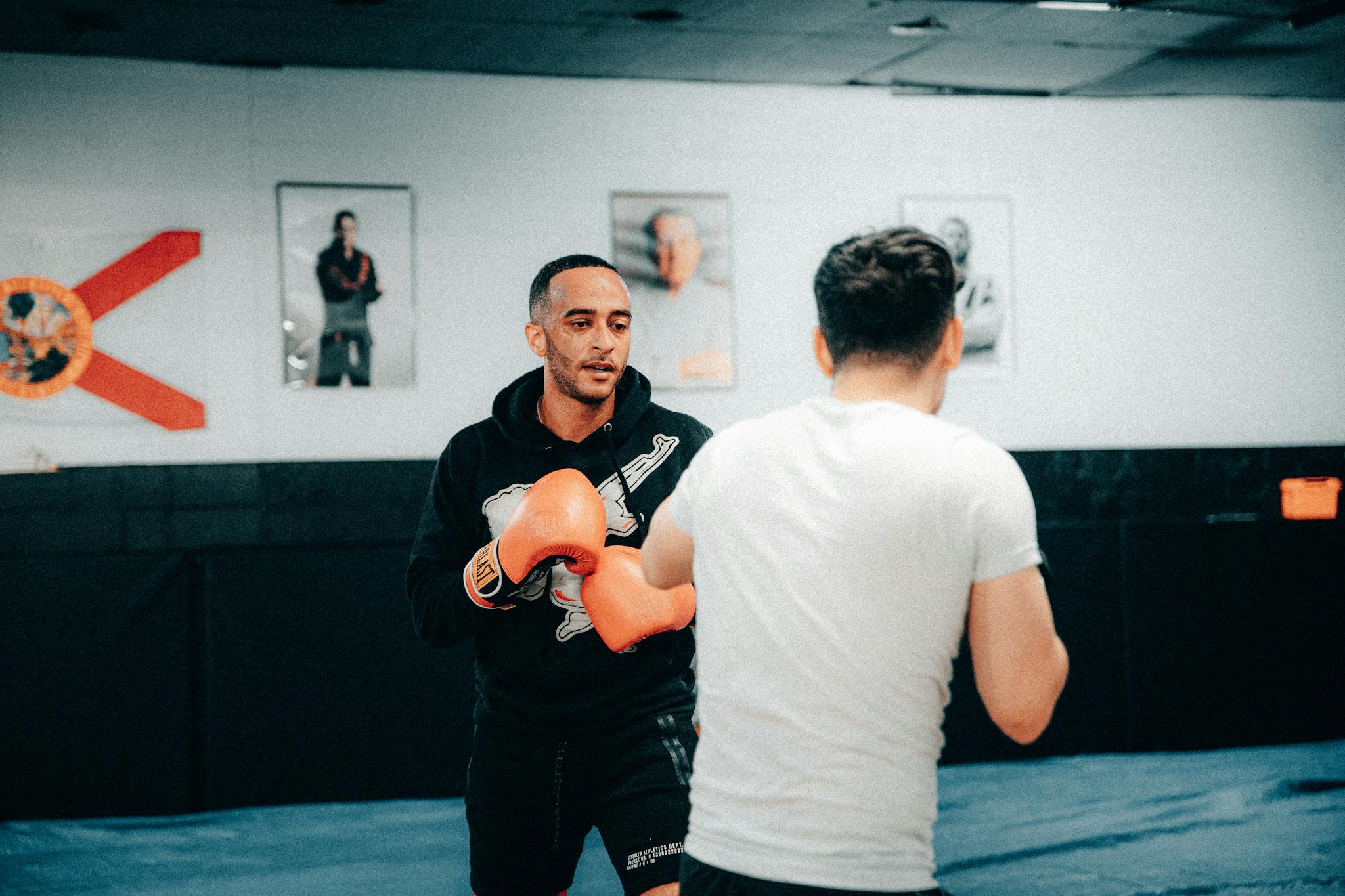 Boxing training session with two men practicing in a gym setting.