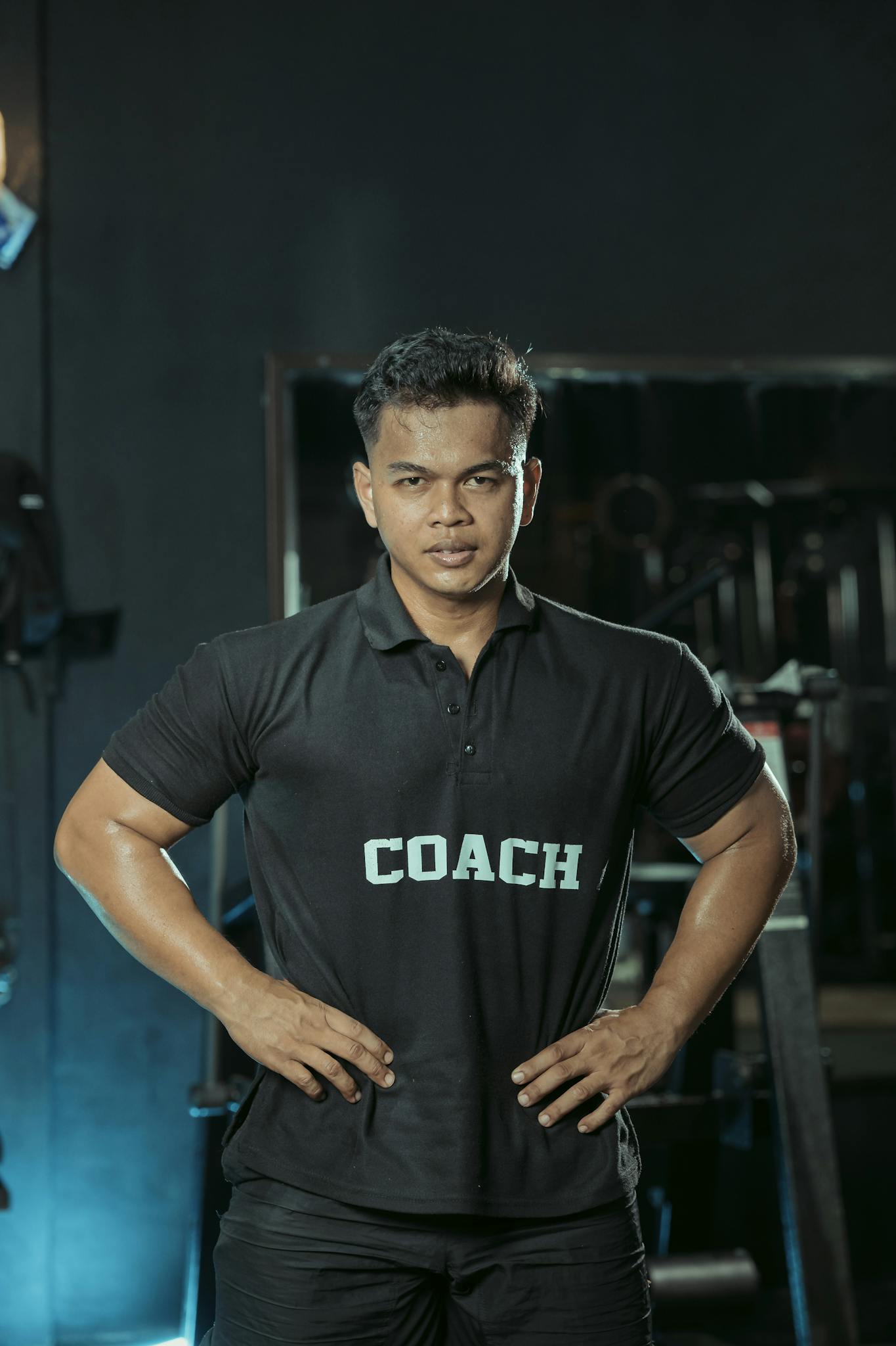 Confident fitness coach posing in a gym, emphasizing strength and expertise. Perfect for health and fitness themes.